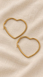 Amora Hoops – slim gold-tone heart-shaped hoop earrings on beige linen